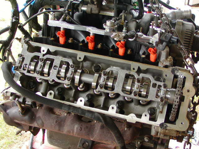 SOHC V8 with valve cover off showing camshaft, roller followers, timing chain and orange injectors