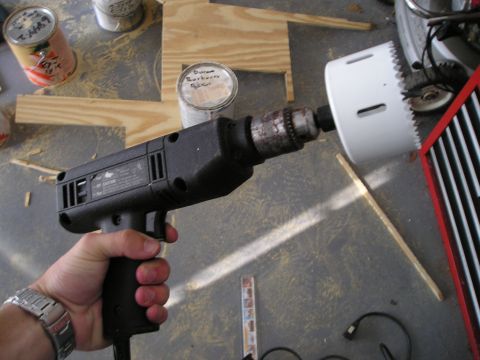 1996 Ford Bronco - A power drill with a hole saw attachment is held by a person in a workshop setting.