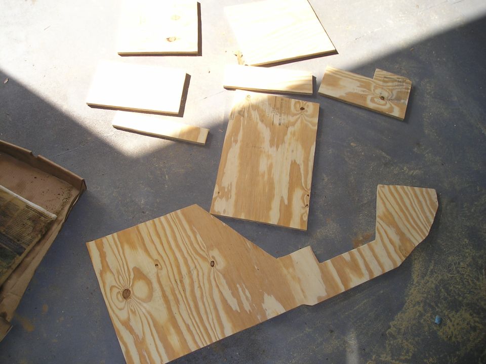 Several cut plywood panels and templates laid out on a concrete garage floor