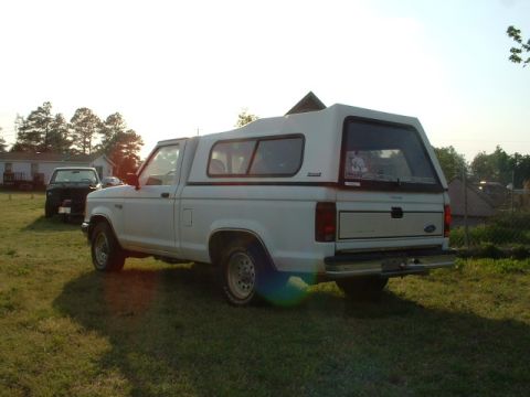 1992 Ford Ranger - White 1992 Ford Ranger pickup truck with a camper shell is parked in a grassy area next to a house.