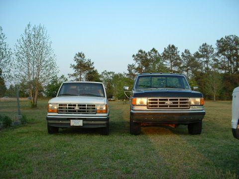 1992 Ford Ranger - A white 1992 Ford Ranger and a black Ford F-series truck are parked side-by-side in a grassy area.