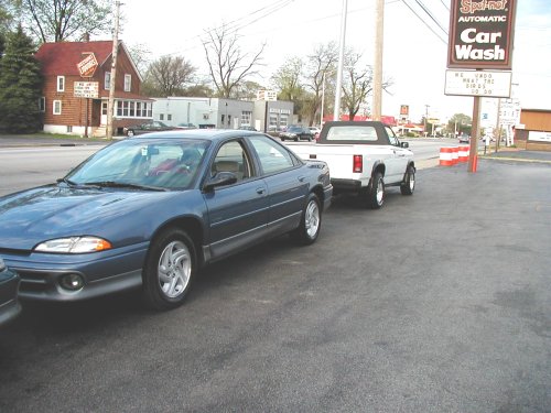 1995 Dodge Intrepid sedan parked next to a white pickup truck on asphalt