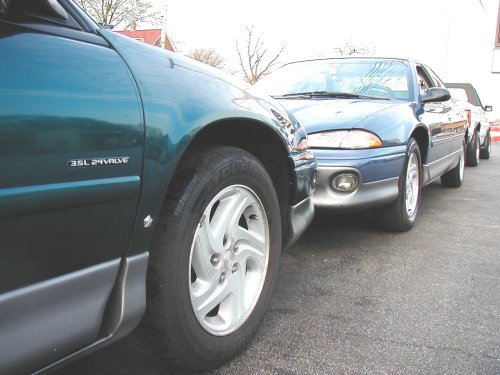 Green 1995 Dodge Intrepid fender with 3.5L 24 VALVE badge, blue 1995 Dodge Intrepid in background