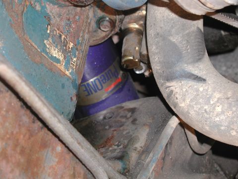 1985 Ford Bronco - A close-up view of a purple oil filter with visible text, situated among various engine parts and hoses.
