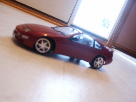1998 Mercury Sable - A small, red toy car sits on a flat surface near a window.