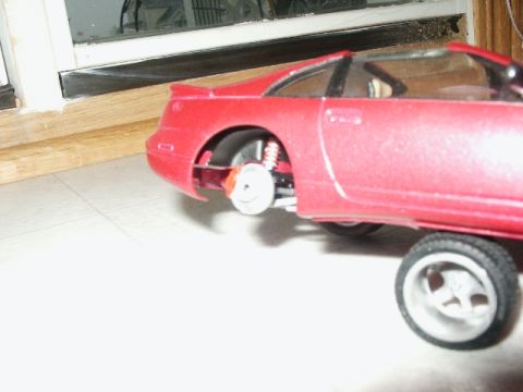 1998 Mercury Sable - A close-up view of a red model car's rear wheel and suspension system.