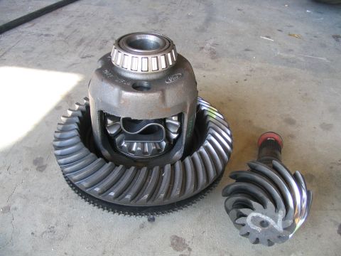 1989 Ford Bronco - Differential and gears are laid out on a concrete surface, disassembled from a vehicle.