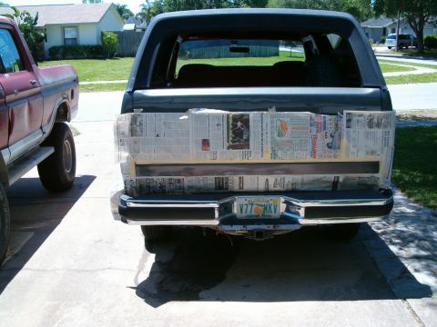 1991 Ford Bronco - 1991 Ford Bronco tailgate covered in newspaper, parked next to another truck.