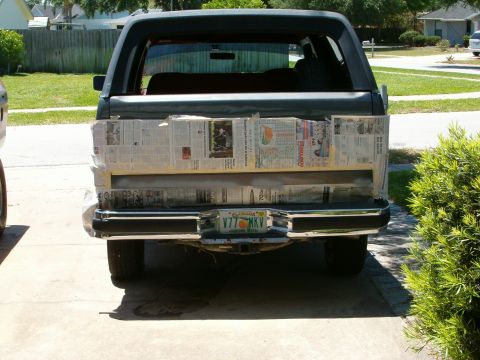 1991 Ford Bronco - Rear view of a dark green Ford Bronco with its tailgate covered in newspaper, likely for a repair or painting project.