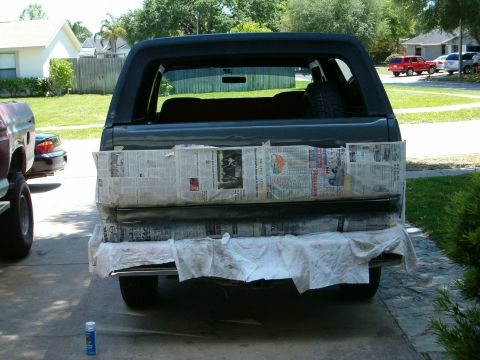 1991 Ford Bronco - This dark SUV's tailgate is covered in newspaper and drop cloths, suggesting preparation for repair work.