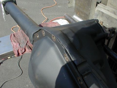 1983 Ford Bronco - Close-up of a freshly painted black axle housing center section and axle tube, resting on a stand outdoors with a red shop rag draped over…