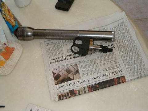 1991 Ford Bronco - A flashlight and a car part are placed on a newspaper, with a portion of a bag of peanuts visible.