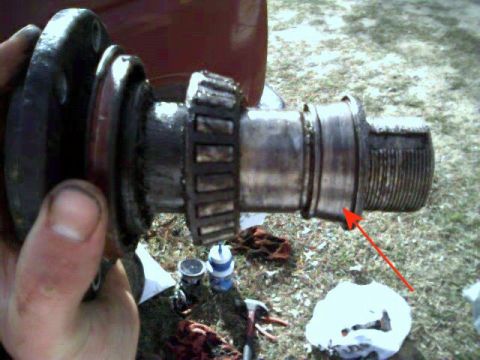 1986 Ford Bronco - A close-up view of a greasy vehicle axle part, with a red arrow indicating a seal.