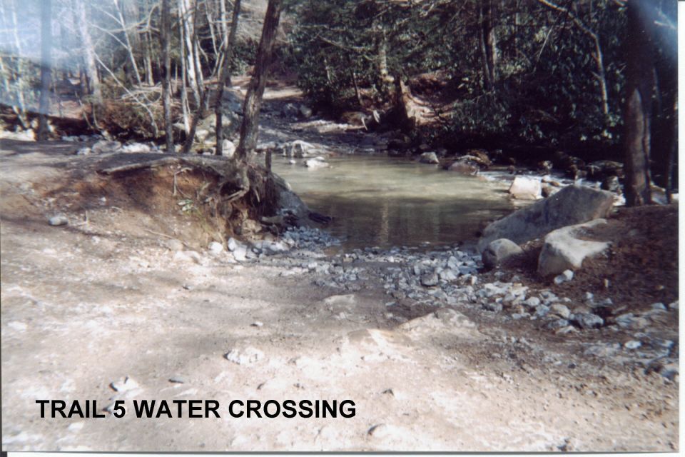 Rocky creek crossing on a forest trail labeled Trail 5 Water Crossing; no vehicle shown