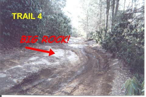 1984 Ford Bronco - A muddy, off-road trail marked as 'TRAIL 4' presents a significant rock obstacle for vehicles.