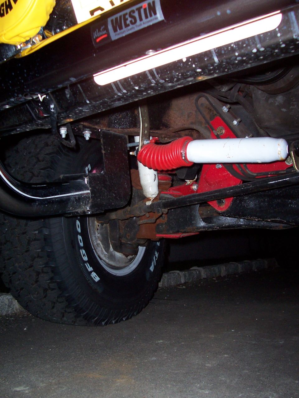 Undercarriage view showing a red bellows shock absorber, black frame rail with Westin sticker, and BFGoodrich tire
