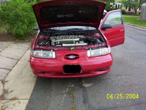 1995 Ford Taurus - Front view of a red 1995 Ford Taurus SHO with its hood and driver's door open, revealing the engine compartment.