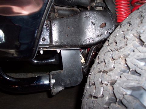 1990 Ford Bronco - Close-up view of a vehicle's undercarriage, showing the chassis, suspension, and tire.