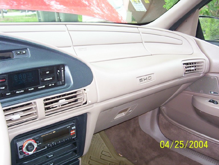 Dashboard of a 1995 Ford Taurus with SHO badging, tan interior, and aftermarket stereo