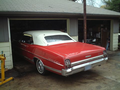 1967 Ford Galaxie - The rear of a red 1967 Ford Galaxie convertible with a white top is visible as it is parked in a garage.