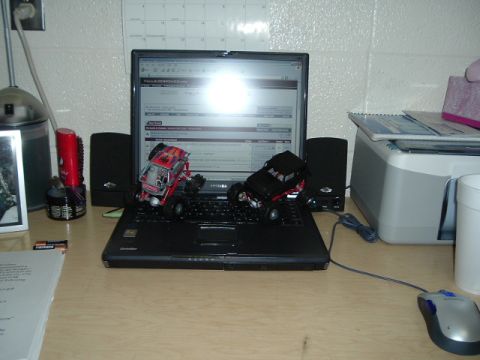 1989 Ford Bronco - Two toy monster trucks are positioned on a laptop keyboard, with one red and one black vehicle visible.