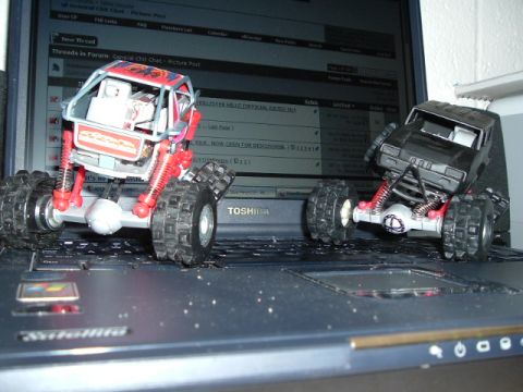 1989 Ford Bronco - Two remote-controlled rock crawler trucks are positioned on a laptop keyboard.