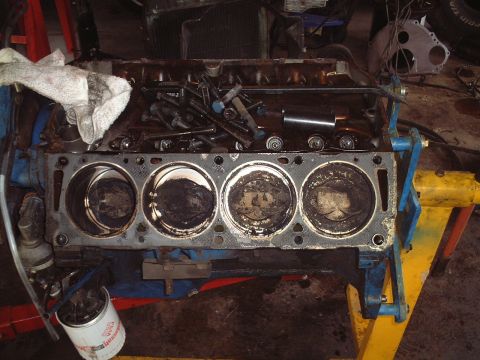 1967 Ford Galaxie - The engine block is disassembled, showing the pistons and cylinders. Tools and parts are nearby.
