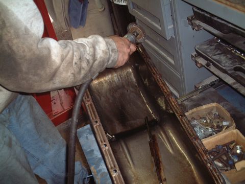 1967 Ford Galaxie - Cleaning a greasy oil pan with a wire brush attachment on a tool.