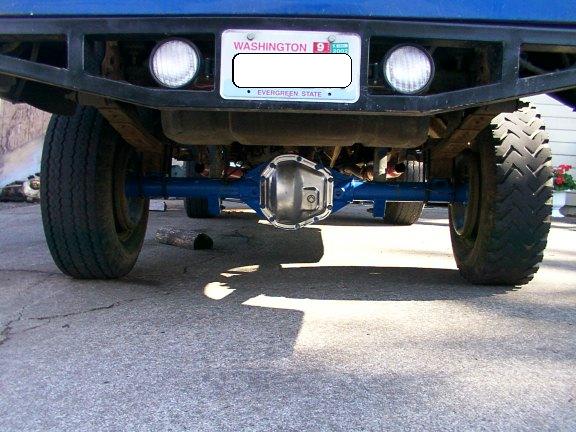 Underside rear view of a blue truck showing a blue-painted solid rear axle and bare-metal diff cover