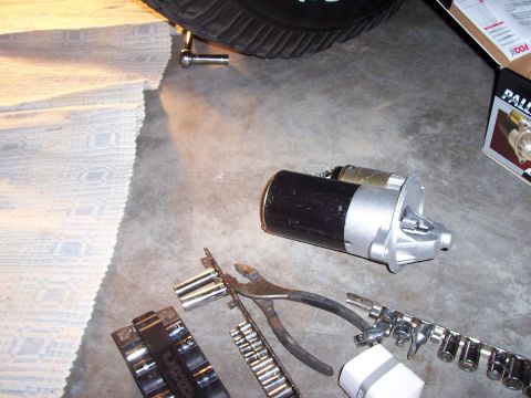 1994 Ford Bronco - A starter motor is shown with various tools, including sockets and pliers, on a concrete floor.