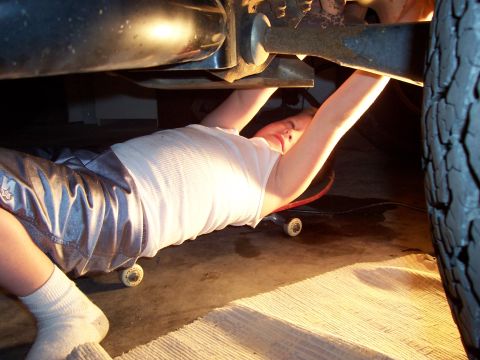 1994 Ford Bronco - Working on the underside of a vehicle, using a skateboard for mobility.