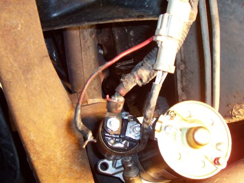 1994 Ford Bronco - Close-up view of a vehicle's starter motor and associated wiring, with visible rust on nearby components.