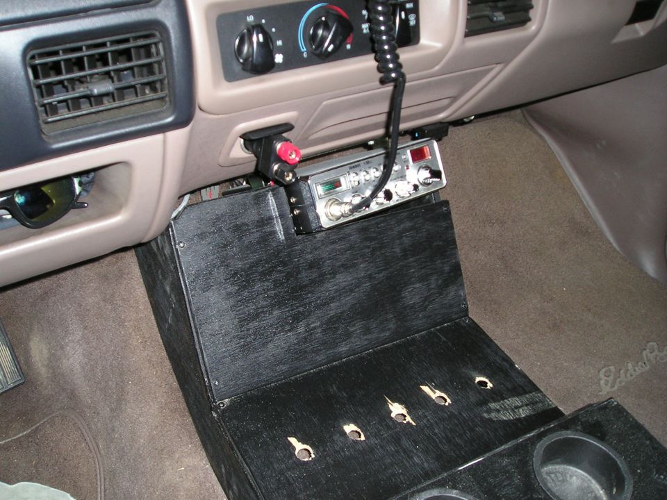 Truck center console with mounted CB radio and switch panel over tan carpet