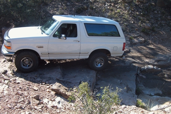 1995 Ford Bronco driving over rocks on a trail