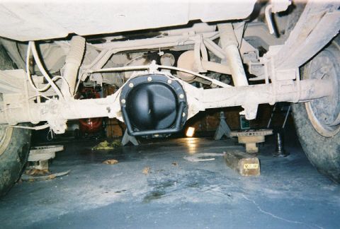 1983 Ford Bronco - Vehicle's rear differential and suspension components are visible, supported by jack stands in a garage.