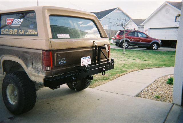 Lifted brown and tan Ford Bronco with custom black steel rear bumper and swing-out tire carrier