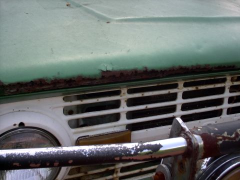 1972 Ford Bronco - The front grille and hood of a green 1972 Ford Bronco show significant rust and peeling paint.