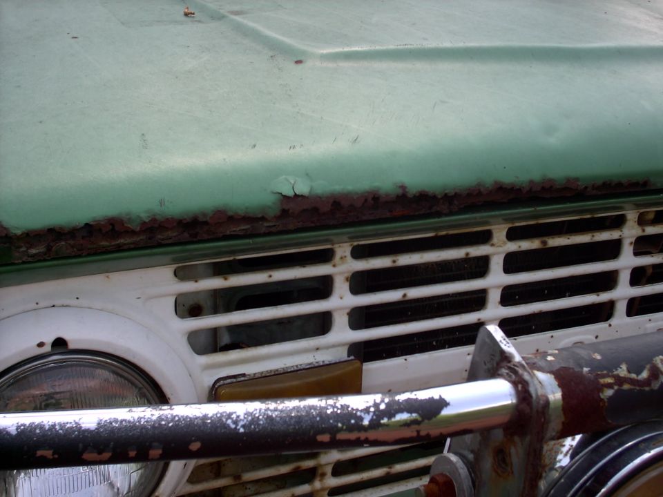 Green 1972 Ford Bronco with rusted hood edge and white grille