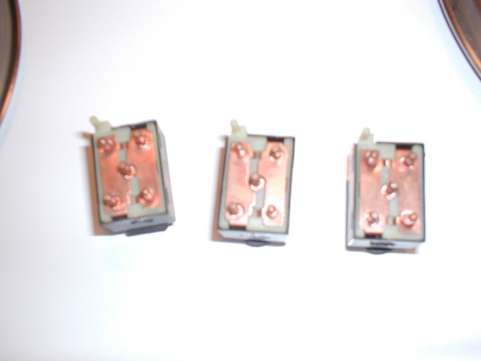 Three automotive electrical switches with copper terminals are shown against a white background