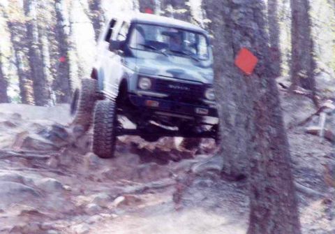 1989 Ford Bronco - A Suzuki Samurai navigates a challenging off-road course through a wooded area.