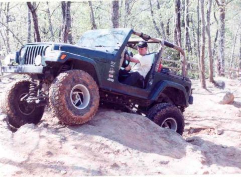 1989 Ford Bronco - A driver navigates a Jeep Wrangler over a rocky, off-road trail.