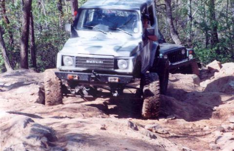 1989 Ford Bronco - A Suzuki Samurai navigates a challenging rocky trail, with another off-road vehicle visible behind it.