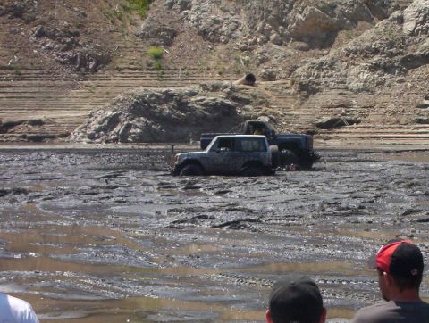 2000 Ford F-450 - Off-road vehicles are stuck in thick mud, with spectators observing the scene.