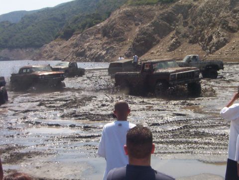 2000 Ford F-450 - Multiple vehicles are stuck in the mud, creating large splashes as they attempt to drive through the mire.