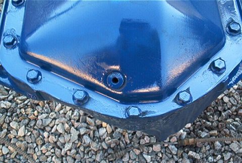 1986 Ford Bronco - A blue painted differential axle housing sits on a bed of gravel.