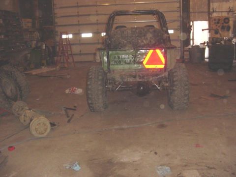 1992 Ford Bronco - This off-road vehicle, covered in mud, is parked inside a garage with a reflective safety triangle on its rear.