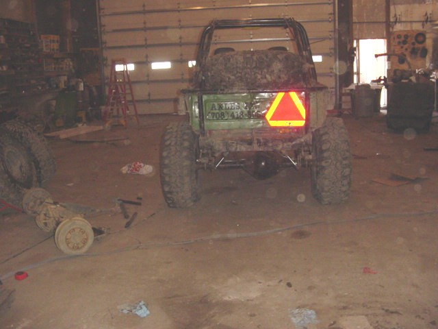Muddy off-road vehicle in a garage with a reflective triangle on the back