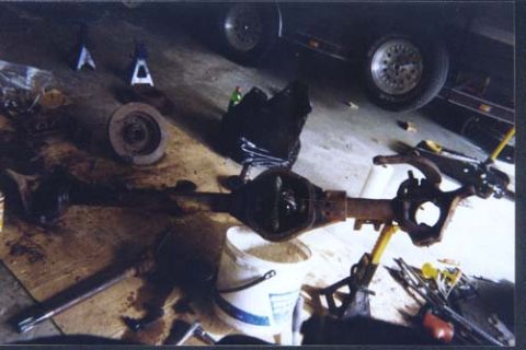 1996 Ford Bronco - A disassembled differential and axle assembly is laid out on a workbench with various tools.