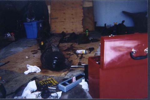 1996 Ford Bronco - Engine component resting on a shop floor, next to a red toolbox and blue storage bin.