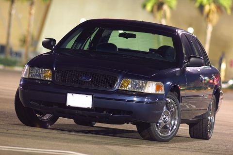 1998 Ford Crown Victoria - dark blue Ford Crown Victoria sedan photographed front three-quarter at night under lights in a parking lot.